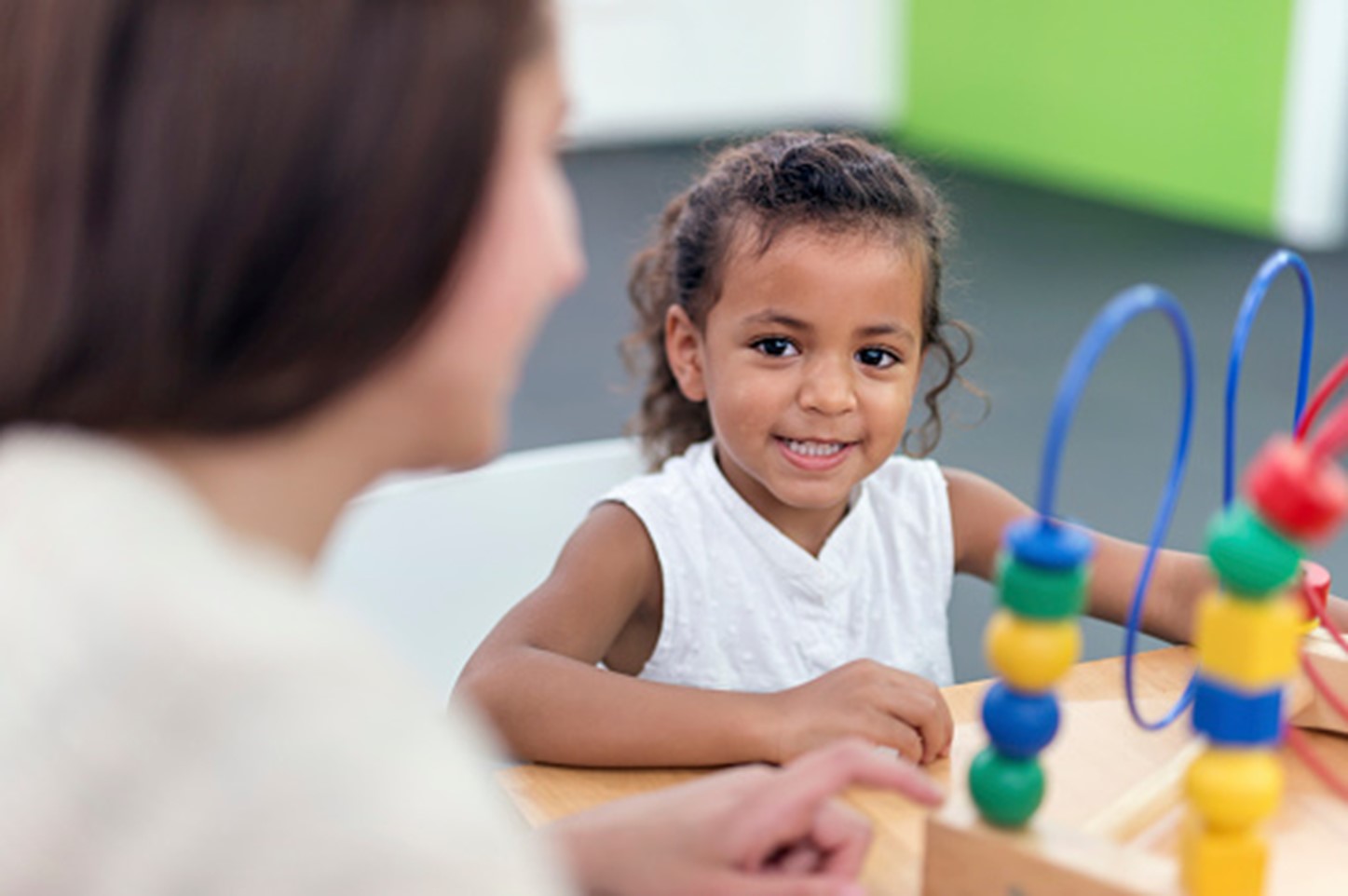 Child playing with colorful bead maze toy, promoting developmental learning at South Shore Therapies.