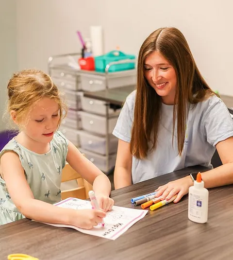 A therapist assisting a child in a therapy room at South Shore Therapies.